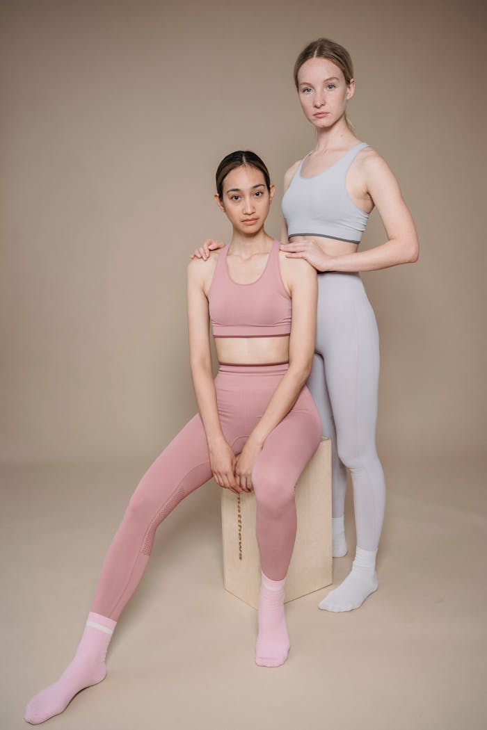 Two diverse women in pastel activewear posing against a neutral background.